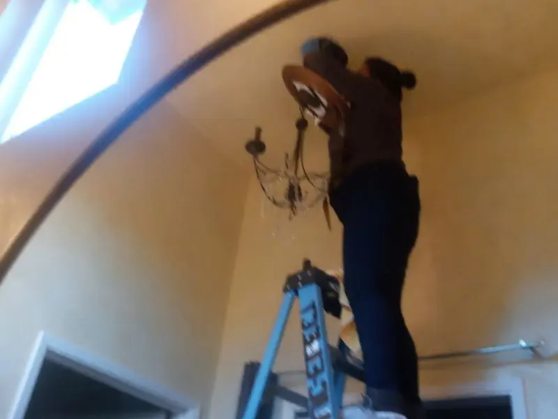 Electrician installing a chandelier in a Pecan Acres residence
